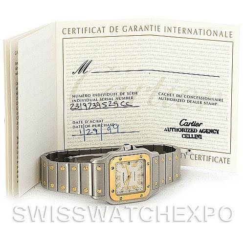 The image shows a Cartier Santos W20058C4 Men's Stainless Steel Silver Dial W20058C4 Men's Stainless Steel Silver Dial watch lying flat, with the certificate of guarantee positioned behind it.