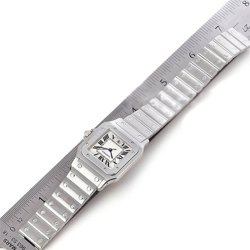 The image shows a Cartier Santos W20060D6 Men
s Stainless Steel Silver Dial W20060D6 Men
s Stainless Steel Silver Dial watch from a top-down angle, with the face and full metal strap aligned next to a ruler.