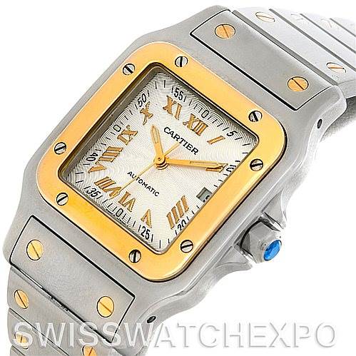 The image shows a close-up of the face and part of the strap of a Cartier Santos W20058C4 Men
s Stainless Steel Silver Dial W20058C4 Men
s Stainless Steel Silver Dial watch, highlighting its gold bezel and screws.