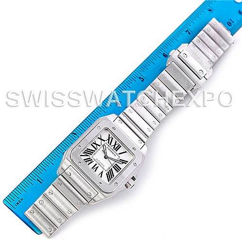 The image shows a full view of a Santos model by Cartier watch laid flat next to a blue ruler for size comparison.