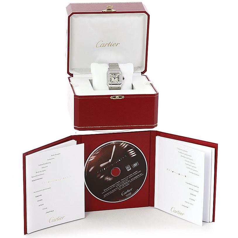The image shows a Cartier Santos W20060D6 Men
s Stainless Steel Silver Dial W20060D6 Men
s Stainless Steel Silver Dial watch placed in an open red box, accompanied by manuals and a CD.