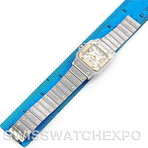 The Santos model by Cartier is shown from a top-down angle, displaying the full watch including the face and metal band.