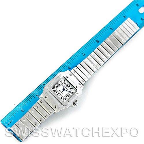 The image shows a top-down view of a Cartier Santos W20098D6 Men
s Stainless Steel Silver Dial W20098D6 Men
s Stainless Steel Silver Dial watch alongside a blue ruler for scale.