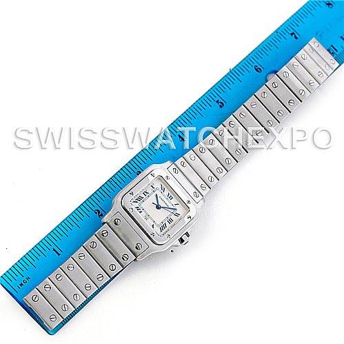 The image shows a Cartier Santos W20060D6 Men's Stainless Steel Silver Dial W20060D6 Men's Stainless Steel Silver Dial model watch laid flat with its face and entire bracelet band displayed alongside a blue ruler.