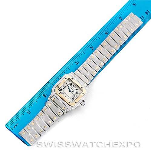 This image shows a Santos model by Cartier watch laid out flat with a ruler measuring its length.