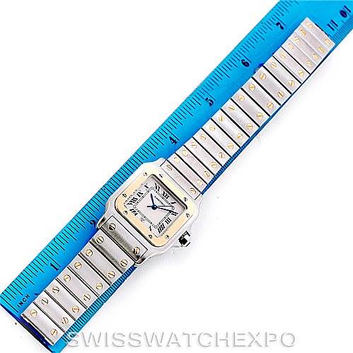 The image shows a top-down view of a Cartier Santos W20011C4 Men
s Stainless Steel Silver Dial W20011C4 Men
s Stainless Steel Silver Dial watch, including the face, bezel, and entire bracelet placed next to a blue ruler.