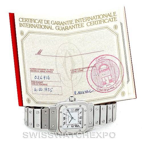 The image shows a Cartier Santos Men
s Stainless Steel White Dial Men
s Stainless Steel White Dial watch placed in front of an international guarantee certificate.