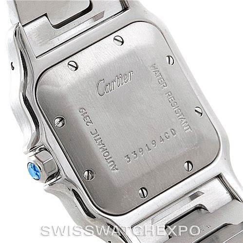 The image shows the back case and part of the band of a Cartier Santos W20058C4 Men's Stainless Steel Silver Dial W20058C4 Men's Stainless Steel Silver Dial watch, highlighting its screws, inscriptions, and blue crown.