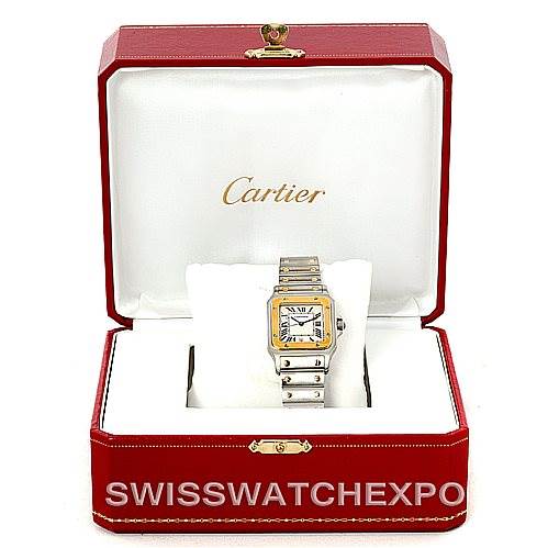 The image shows a Santos model by Cartier inside a red Cartier watch box, with the watch face and bracelet visible.