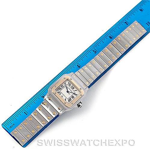 This image shows a top-down view of a Santos model watch by Cartier beside a ruler, highlighting the band and face.