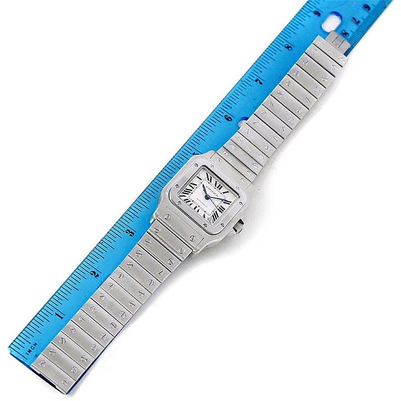 The Cartier Santos W20098D6 Men's Stainless Steel Silver Dial W20098D6 Men's Stainless Steel Silver Dial watch is shown from a top-down angle, placed alongside a blue ruler for scale.