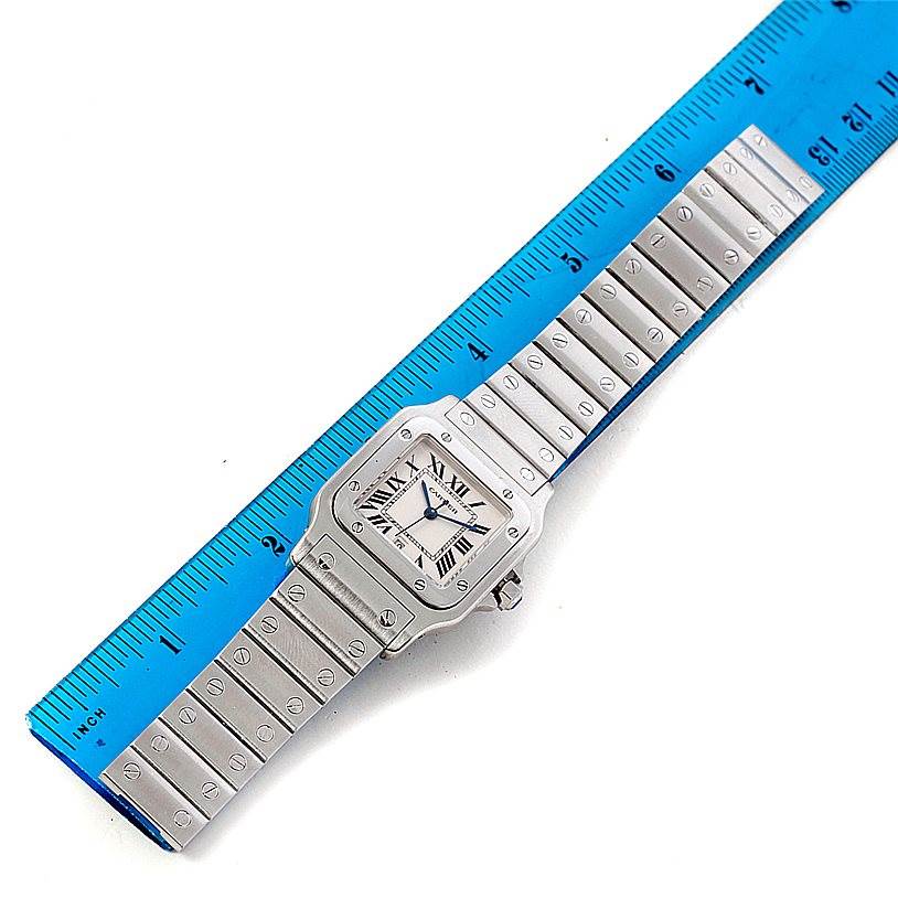 This image shows a Santos model by Cartier from a top-down angle, including the watch face, bezel, and full bracelet next to a ruler.