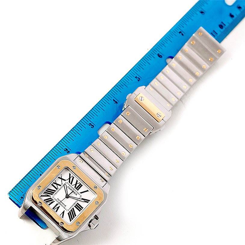 This image shows a Santos model watch by Cartier, with the dial, bezel, and full bracelet, measured against a blue ruler.