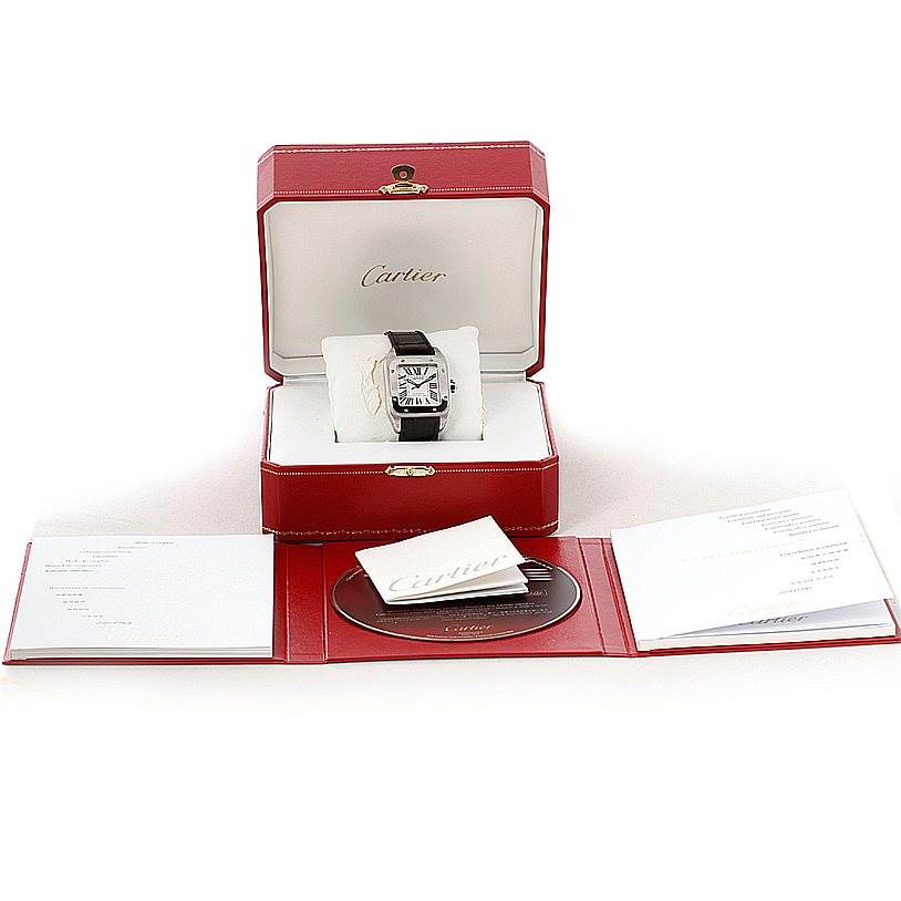 The image shows a Cartier Santos W20106X8 Men
s Stainless Steel Silver Dial W20106X8 Men
s Stainless Steel Silver Dial watch in its open box, along with accompanying booklets and a CD.