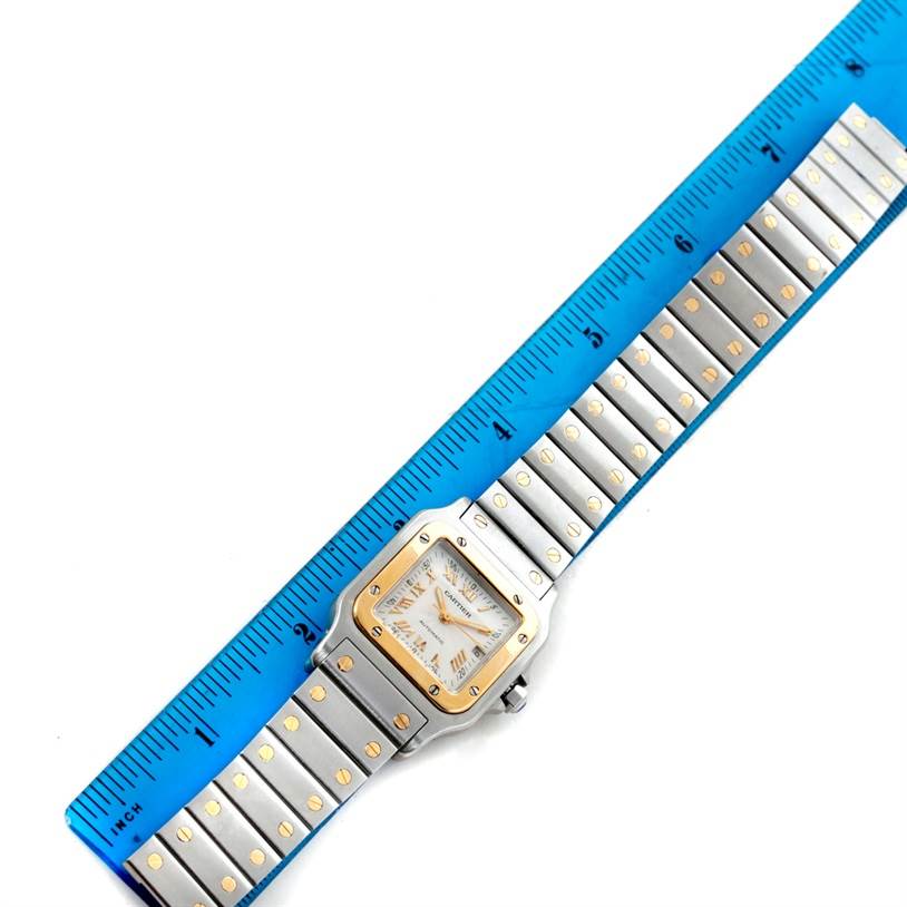 The Cartier Santos W20058C4 Men
s Stainless Steel Silver Dial W20058C4 Men
s Stainless Steel Silver Dial watch is shown from above, highlighting its face, bezel, and bracelet alongside a ruler.