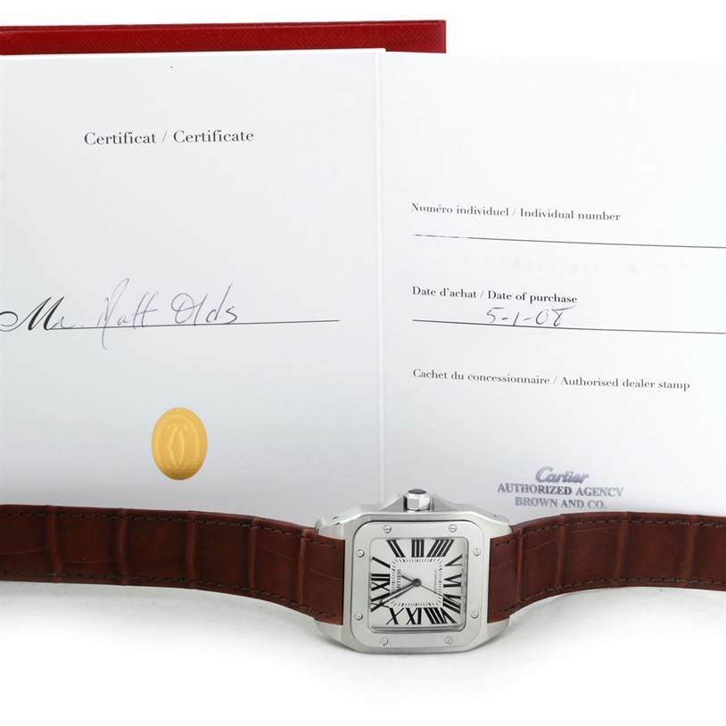 A Cartier Santos W20073X8 Men
s Stainless Steel Silver Dial W20073X8 Men
s Stainless Steel Silver Dial watch is shown from the front, with a leather strap and certificates in the background.