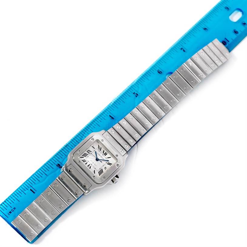 The Cartier Santos W20055D6 Men
s Stainless Steel Silver Dial W20055D6 Men
s Stainless Steel Silver Dial watch is shown from a top view, displaying the entire face and bracelet alongside a ruler for scale.