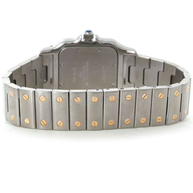 The image shows the back of a Santos model by Cartier, focusing on the metal bracelet with gold screws and the case back.