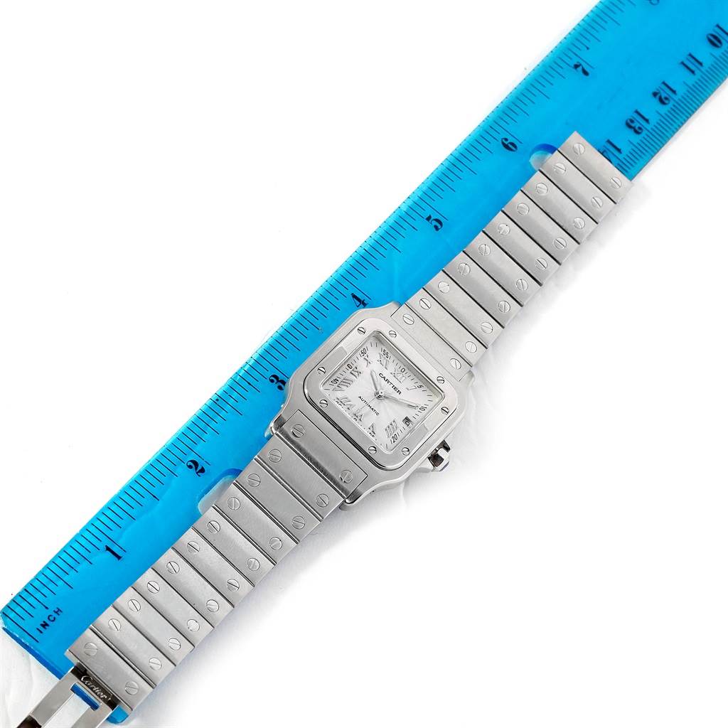 The image shows a top-down view of a Cartier Santos W20055D6 Men's Stainless Steel Silver Dial W20055D6 Men's Stainless Steel Silver Dial watch, including the face and metal bracelet, against a blue ruler for measurement.