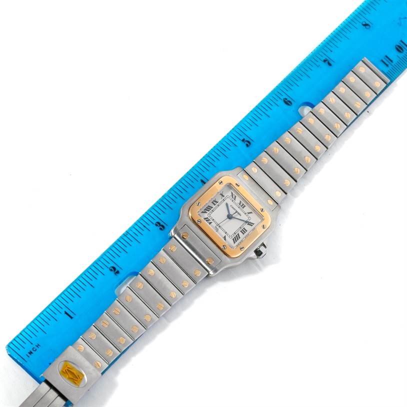 This image shows a top view of a Cartier Santos Stainless Steel Silver Dial Stainless Steel Silver Dial watch next to a blue ruler for scale measurement.