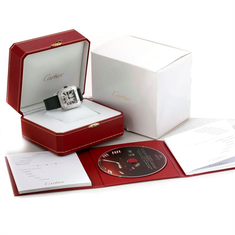 The image shows a Cartier Santos W20073X8 Men's Stainless Steel Silver Dial W20073X8 Men's Stainless Steel Silver Dial watch in an open box, with additional packaging and documentation, including a CD.