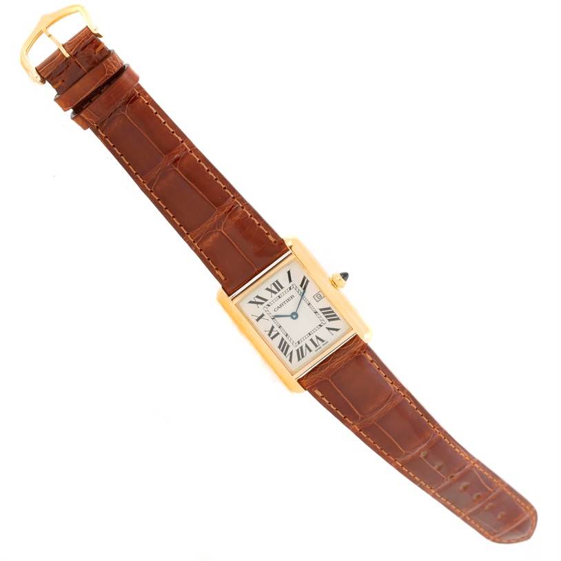 The Cartier Tank Louis W1529756 Men's Yellow Gold Silver Dial W1529756 Men's Yellow Gold Silver Dial watch is shown from a top-down angle, displaying its face, brown leather strap, and gold buckle.
