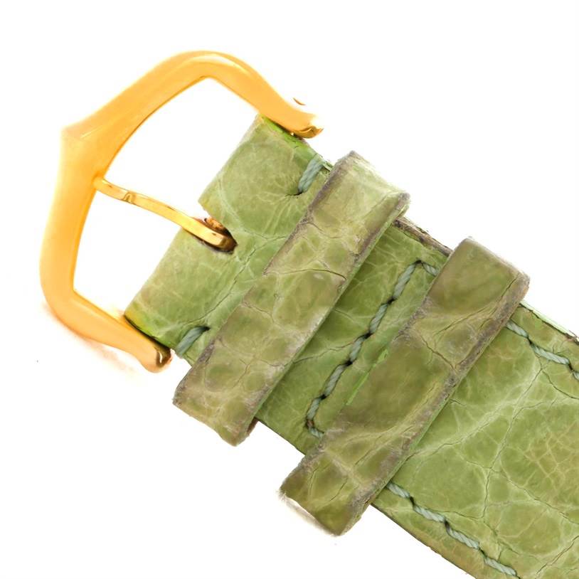 The image shows a close-up of the green leather strap and gold buckle of the Tank Louis model by Cartier.