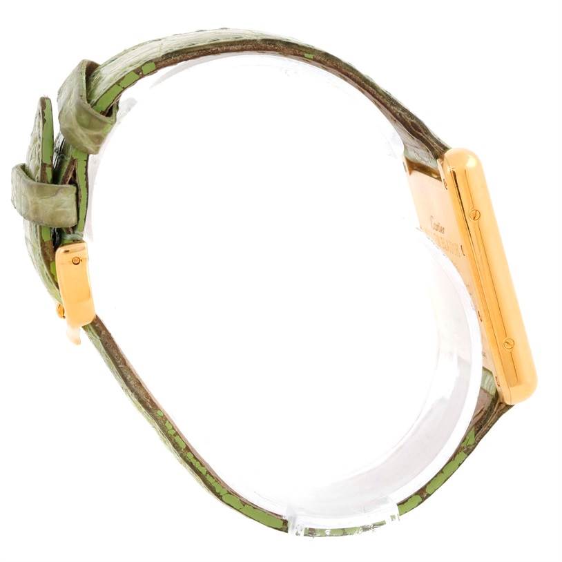 The Cartier Tank Louis W1529756 Men's Yellow Gold Silver Dial W1529756 Men's Yellow Gold Silver Dial watch is shown from a side angle, highlighting the gold case and green leather strap.