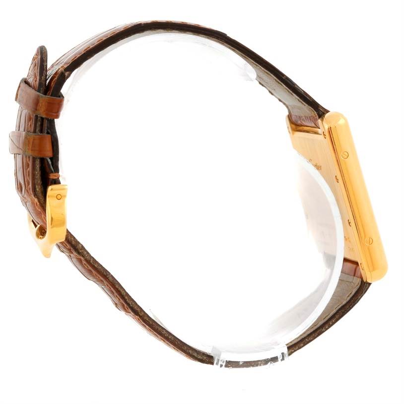 The image shows a side view of a Cartier Tank Louis Men's Yellow Gold Silver Dial Men's Yellow Gold Silver Dial watch, highlighting the brown leather strap and gold case.