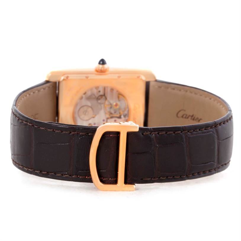 The image shows the back view of the Tank Louis watch by Cartier, displaying the movement and the brown leather strap with a gold buckle.
