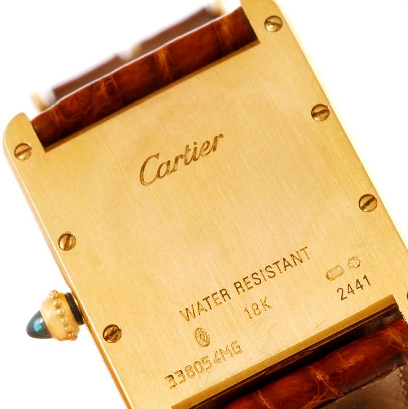 The image shows the back of a Tank Louis watch by Cartier, displaying its engravings and part of the leather strap.