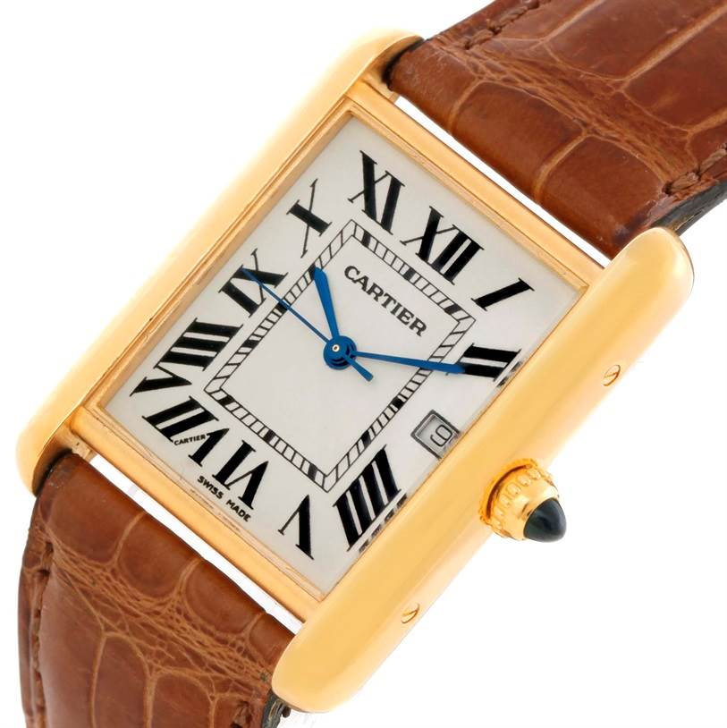 The Tank Louis model by Cartier is shown at an angle, featuring its rectangular gold case, brown leather strap, and crown set with a blue cabochon.