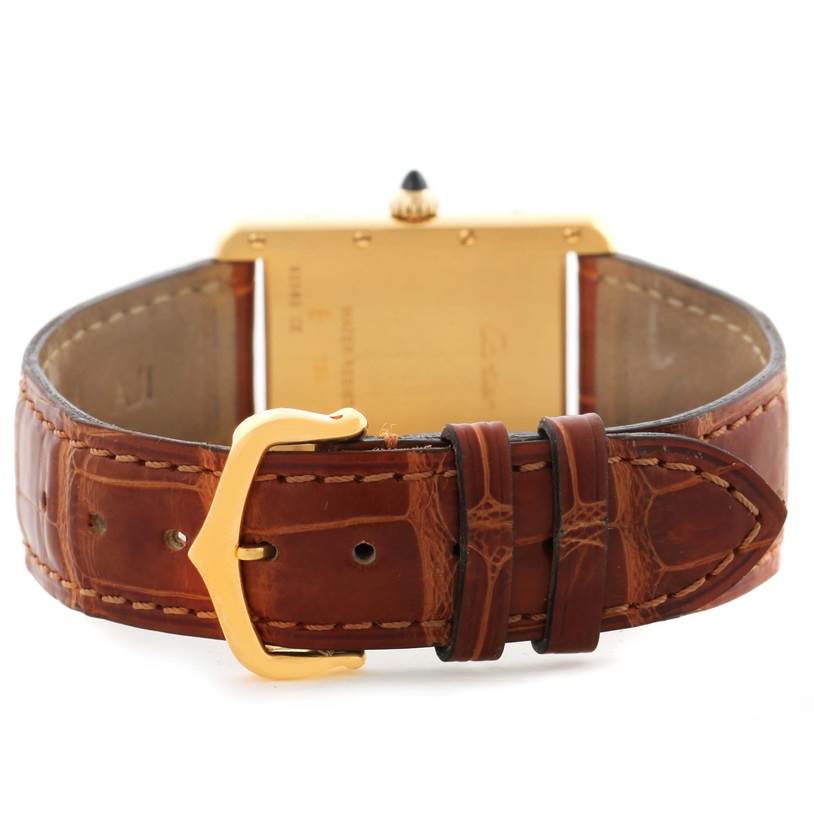 The image shows the back of a Tank Louis watch by Cartier, highlighting its brown leather strap and gold buckle.
