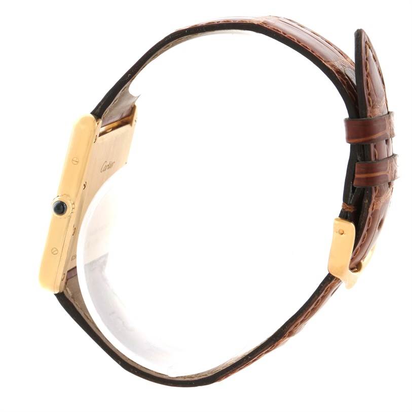 The image shows a side view of a Cartier Tank Louis W1529756 Men's Yellow Gold Silver Dial W1529756 Men's Yellow Gold Silver Dial watch, focusing on the gold case, crown with a blue cabochon, and brown leather strap.