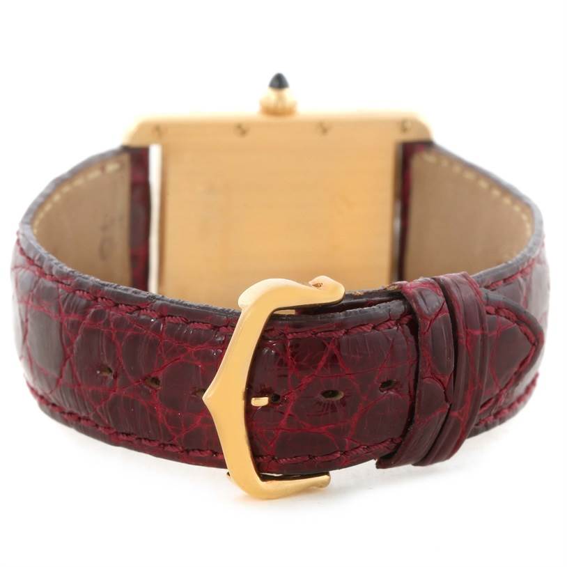 The image shows the back of a Cartier Tank Louis W1529756 Men's Yellow Gold Silver Dial W1529756 Men's Yellow Gold Silver Dial watch with a gold case and a maroon leather strap with a buckle.