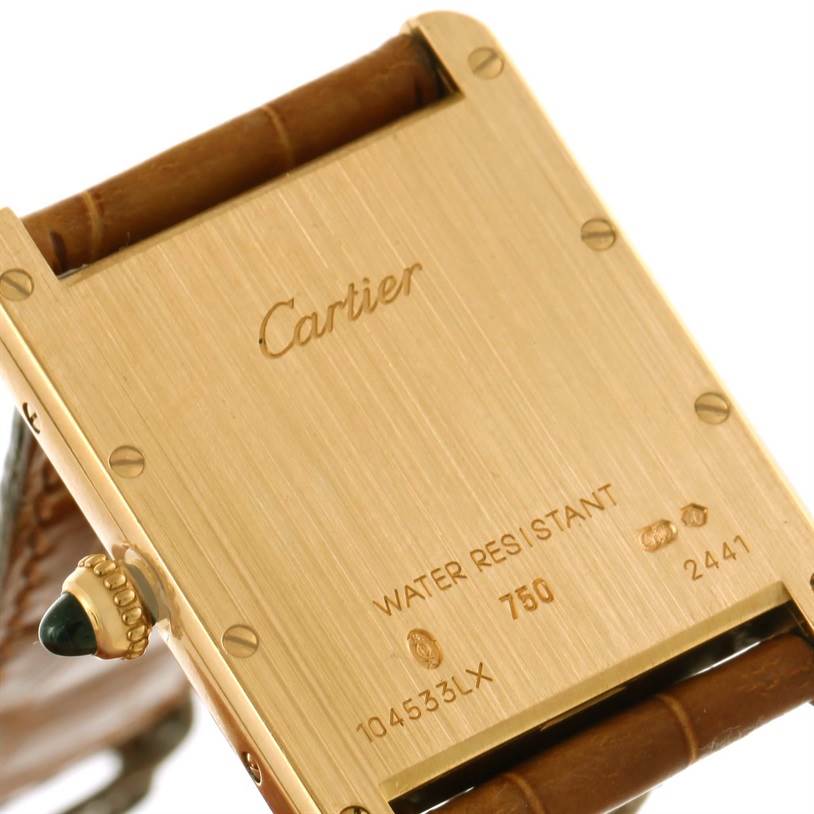 The image shows the back case of a Cartier Tank Louis W1529756 Yellow Gold Silver Dial W1529756 Yellow Gold Silver Dial watch, highlighting the engraved details and part of the leather strap.