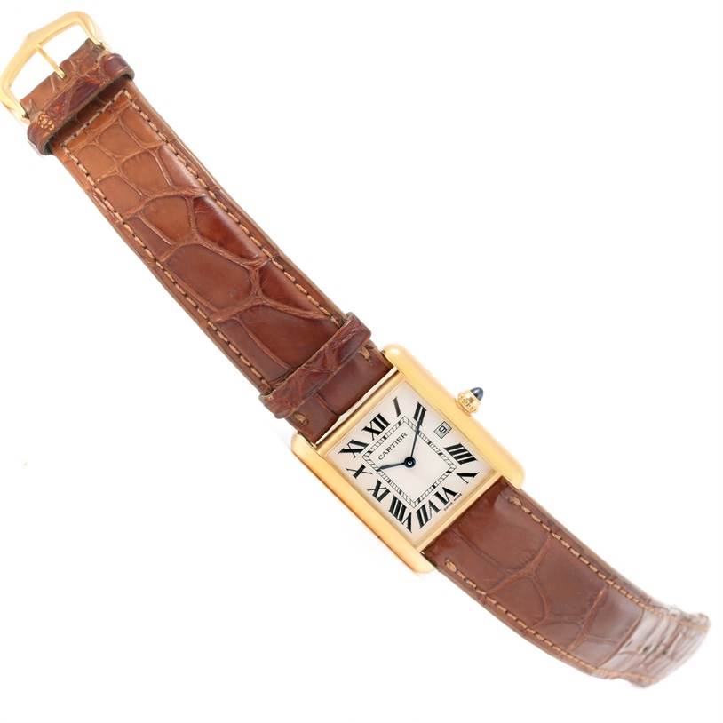 The image shows a Tank Louis model by Cartier with a brown leather strap, gold rectangular case, and white dial with Roman numerals.