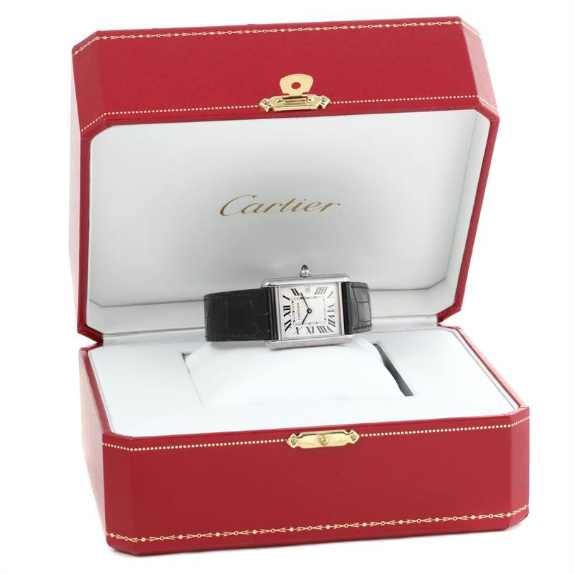 The Tank Louis Cartier watch is displayed in its elegant red and white box showing its face with Roman numerals and black leather strap.