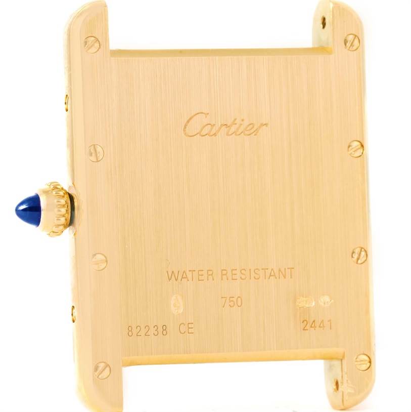 The image shows the back case of a Tank Louis Cartier watch, focusing on its engravings and side crown.