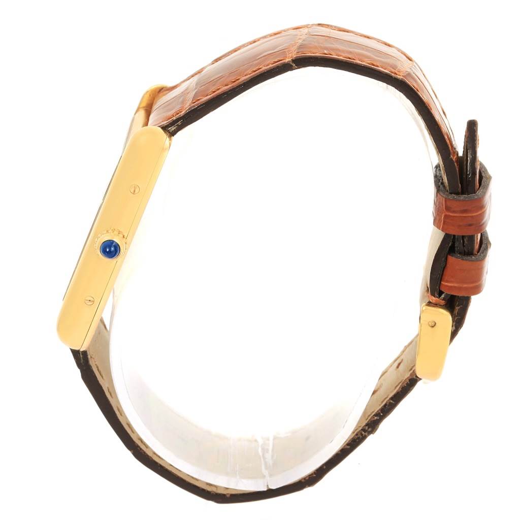 The image shows a side view of the Tank Louis model by Cartier, highlighting the side of the case and the crown with a blue cabochon.