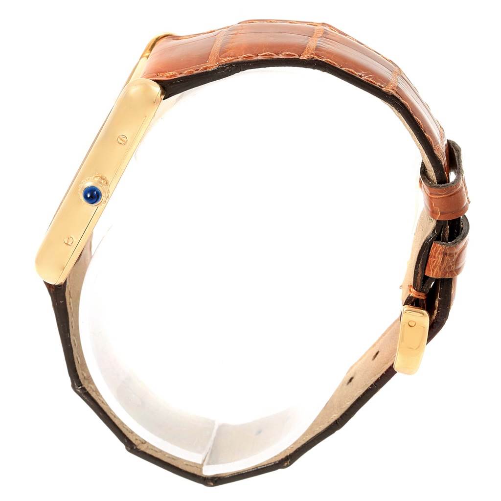 This image shows a side view of the Cartier Tank Louis W1529756 Yellow Gold Silver Dial W1529756 Yellow Gold Silver Dial watch, highlighting the gold case, brown leather strap, and blue cabochon crown.