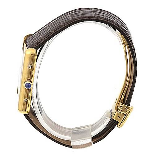 The image shows a side view of a Tank Louis Cartier watch, highlighting its strap, gold casing, and crown with a blue jewel.