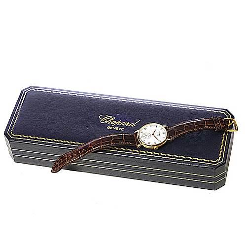 The Tank Louis model by Cartier is displayed lying on a Chopard Genève watch box, showcasing its face and leather strap.