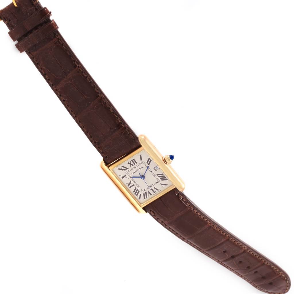 The image shows a Tank Louis model watch by Cartier from an oblique angle, highlighting its brown strap and rectangular gold case.