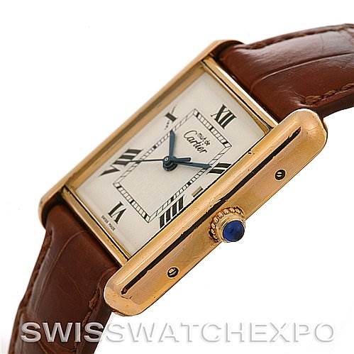 The image shows the Tank Louis model by Cartier from a side angle, highlighting the watch face, brown leather strap, and crown with a blue gemstone.