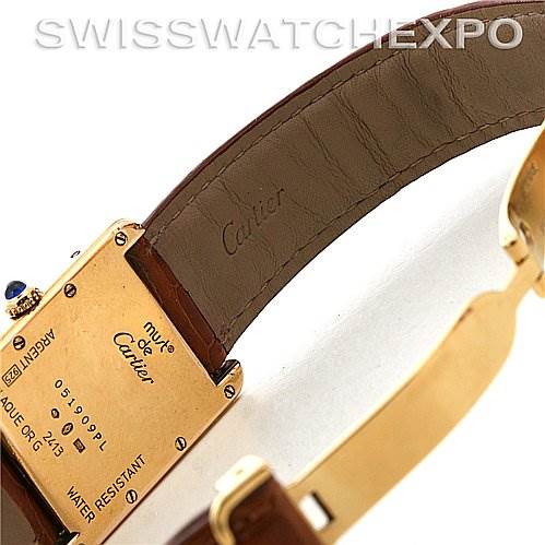 The image shows the back and strap of a Tank Louis watch by Cartier, highlighting its inscriptions and brown leather band.