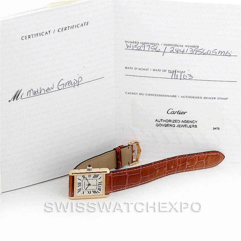 The image shows the Cartier Tank Louis W1529756 Men's Yellow Gold Silver Dial W1529756 Men's Yellow Gold Silver Dial watch and its certificate, positioned with its strap extended.