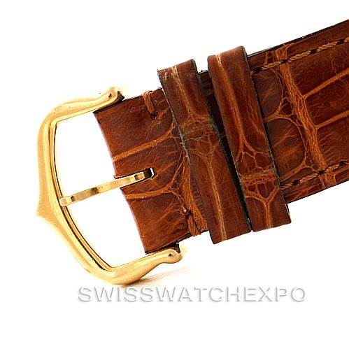 The image shows a close-up of the Tank Louis model by Cartier, focusing on the brown leather strap and gold buckle.