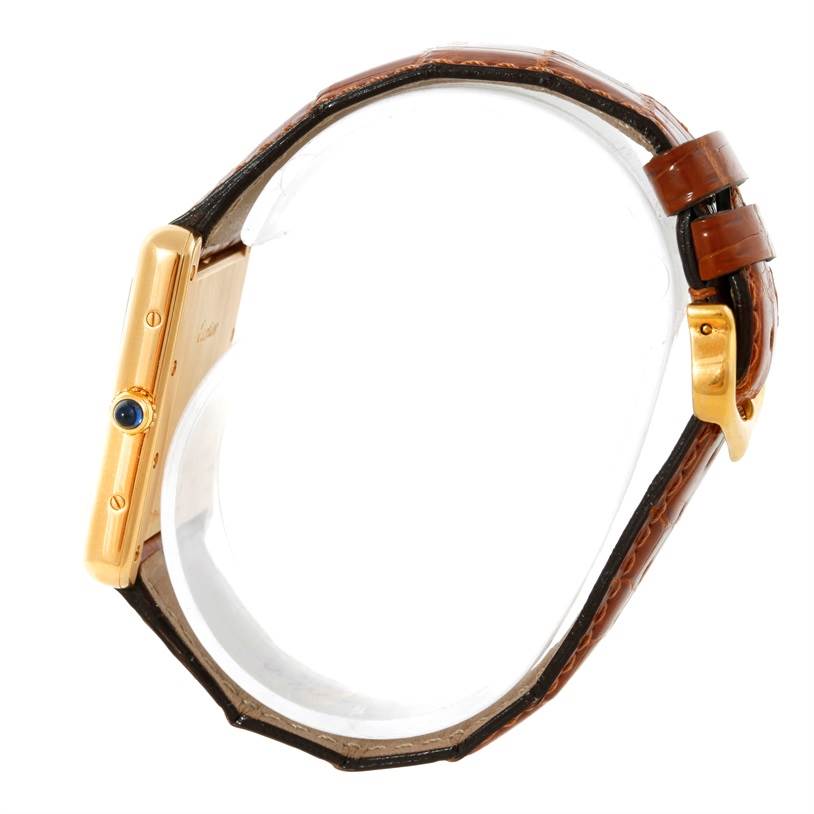 This image shows a side profile of a Cartier Tank Louis W1529756 Men's Yellow Gold Silver Dial W1529756 Men's Yellow Gold Silver Dial watch, highlighting its brown leather strap and gold case with blue cabochon crown.