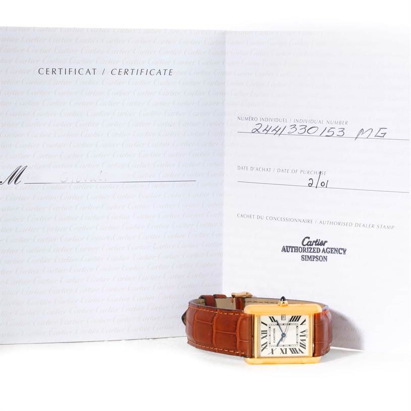The image shows a Cartier Tank Louis W1529756 Men
s Silver Dial W1529756 Men
s Silver Dial watch with a brown leather strap, positioned in front of its certificate and documentation.